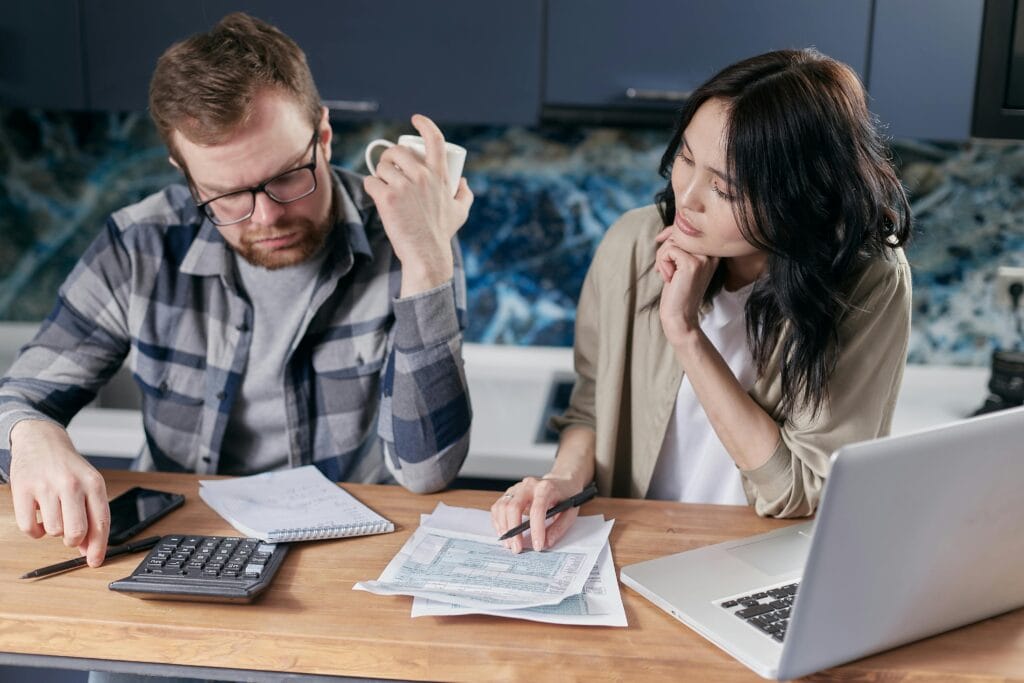 Casal frustrado analisando contas e extratos — representando padrões de comportamento financeiro que dificultam o planejamento pessoal